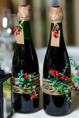 Two green wedding bottles with red wine decorated with flowers, greenery and twine
