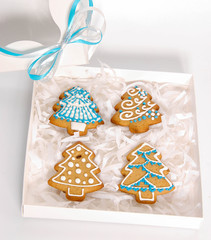 Ginger delicious gingerbread in the form of snowflakes and fir trees in a stylish gift box on a white background. Holiday gift

