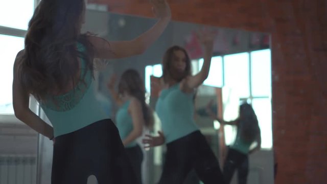 A professional dancer dances in the dance hall among the mirrors. young attractive girl in a glass labyrinth. pleasant daylight with a training hall. Modern choreography. 4k