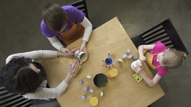 Medium wide shot of two little girls hugging in a ceramic studio