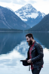Fototapeta na wymiar Stylish tattoed Hipster Man enjoys scenic mountain lake in Austria