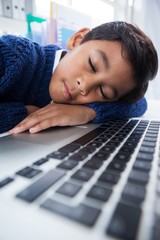 Close up of boy imitating as businessman sleeping on laptop - obrazy, fototapety, plakaty