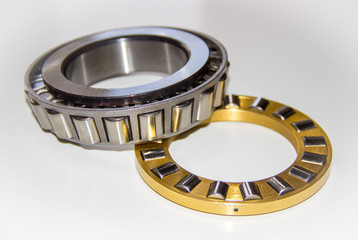 Brass roller cage of a thrust roller bearing and stainless roller cage of a tapered roller bearing with selective focus