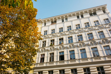 white facaded apartment building with colorful fall tree