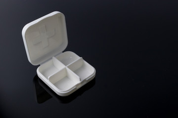 The empty white medicine box on the black reflective plate
