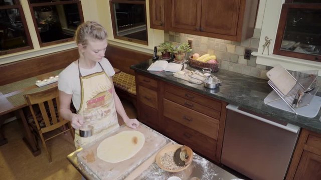 Medium shot of a woman sprinkling dough with brown sugar