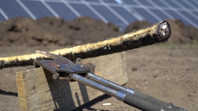 Cropped thick power cable near the jaws against the background of solar panels