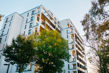 big apartment complex with green trees and warm colored balcony