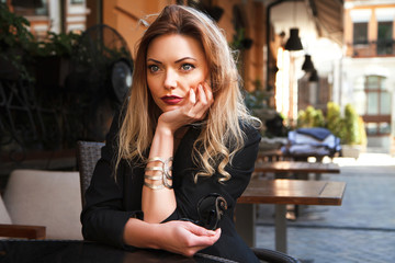 Beautiful and sexy girl in black lingerie and jacket in the summer street cafe