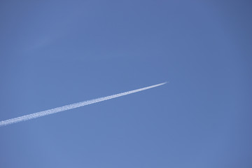 Diagonal airplane trace on a clear blue sky.