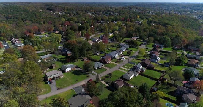 A daytime forward aerial establishing shot of a typical western Pennsylvania residential neighborhood in the early autumn.  	