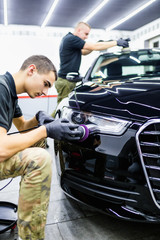 Car detailing - Man with orbital polisher in auto repair shop. 