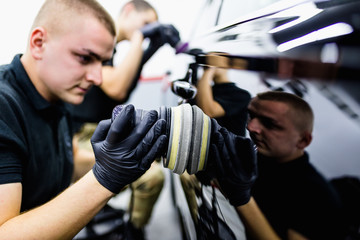 Car detailing - Man with orbital polisher in auto repair shop. 