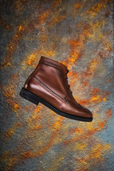 Men's brown leather classic oxford boots on a dark plaster wall texture background. Fashion advertising shoes photos.