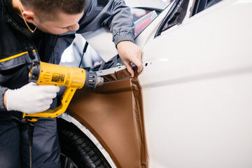 Car wrapping specialist putting vinyl foil or film on car.