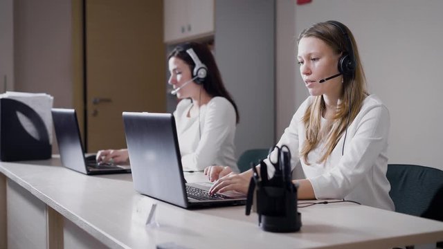 Young female workers of call center with gadgets at desk