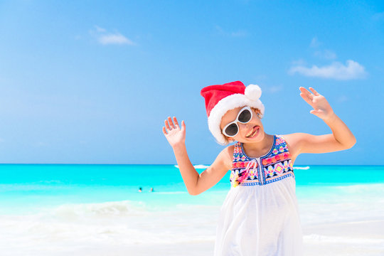 Adorable little girl in Santa hat during Christmas beach vacation. Little kid at Christmas beach holidays