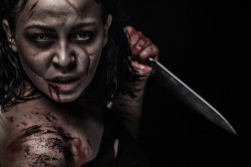 Woman with a knife in the hand close up on dark background. Horror. Halloween poster.