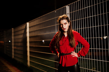 Fototapeta premium Black girl in red shirt and bright make-up on night street outdoor against cage. Halloween theme.