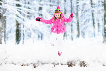 Child playing with snow in winter. Kids outdoors.