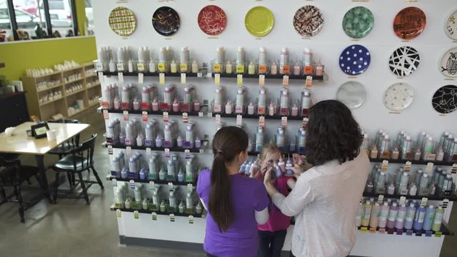 Medium wide shot of mother and her daughters in a ceramic studio