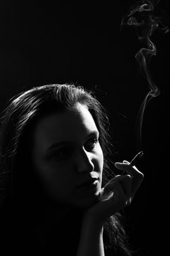 beautiful woman smoking cigarette on black background, monochrome