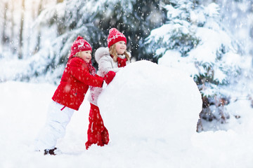 Kids building snowman. Children in snow. Winter fun.