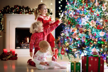Children at Christmas tree. Kids at fireplace on Xmas eve