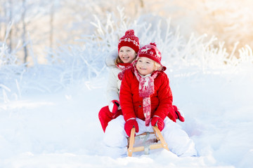 Naklejka na ściany i meble Kids play in snow. Winter sleigh ride for children