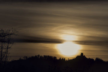 Sunrise with forested mountain silhouette with a castle