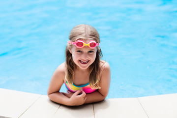 Child with goggles in swimming pool. Kids swim.