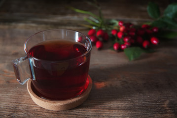 Cup of Tea from rosehip tea and bouquet of rose hips on the wooden background.Seasonal, vitamin drink.Cup Of Tea Or Coffee. Dried Fruits.
