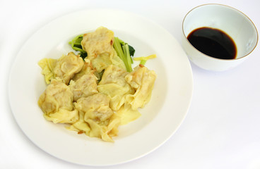 Dumplings on white plate with sweet sauce.