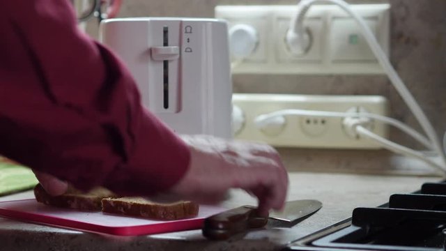 An Elderly Man Cuts The Bread And Puts It In The Toaster