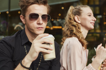 Young adult student people outside in the city drinking coffee and chatting together