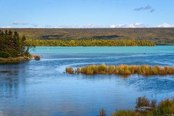 Peaceful landscape at Naknek Lake, Alaska, with glacial blue water, fall color, and a blue sky
