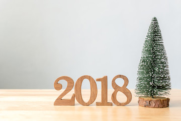 Happy new year 2018, Number wood material on wooden table and christmas tree with white wall background, Copy space