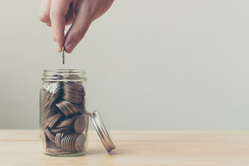 Hand of male or female putting coin in jar for saving money, Concept finance business investment - obrazy, fototapety, plakaty