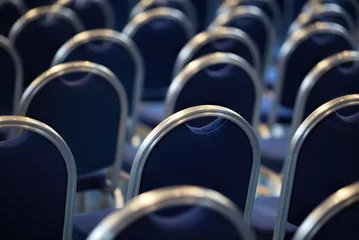 Rows of empty metal chairs in a large assembly hall.Empty chairs in conference hall.Interior meeting room. Back view © MTaitas