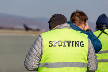 Amateur photographer with the inscription "Spotting" on the back on event outdoor.