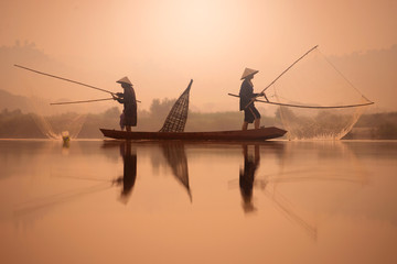 Two fishermen are fishing on the boat at Mekong river in the morning in Nong Khai, Thailand - obrazy, fototapety, plakaty