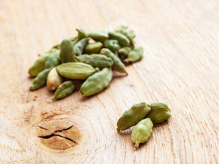 Green cardamom pods on wooden background