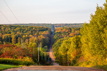 Steep gravel road going through a colorful Wisconsin forest in early autumn
