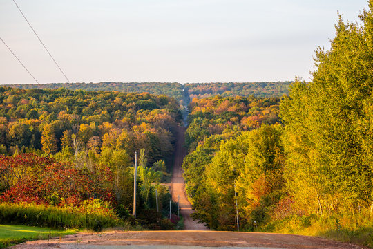 Fototapeta Steep gravel road going through a colorful Wisconsin forest in early autumn