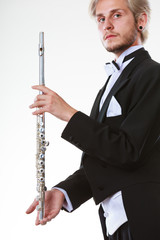 Male flutist wearing tailcoat holds flute