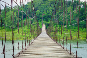 In a long suspension wooden bridge over natural lake. It is at Kaeng Krachan Reservoir National Park in Phetchaburi, Thailand, Southeast Asia.