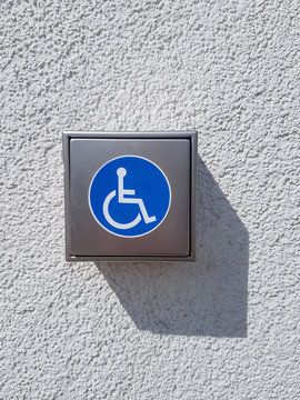 Handschalter aus Edelstahl mit Symbol f&uuml;r Behinderte an einer Hauswand