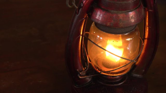 Vintage oil lamp antique stands on the table in the dark. Oil filled lantern in dark room.
