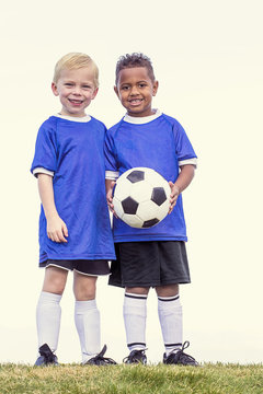 Full length view of two youth recreation league soccer players. Two diverse little boys standing on a grass field