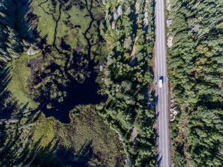 beautiful Canada camper bus driving on road endless pine tree forest with lakes moor land aerial view travel background